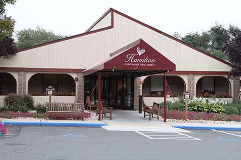 A single-story senior living center with a peaked roof and welcoming entrance under a covered walkway.