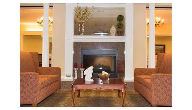 Cozy seating area with two upholstered sofas facing a fireplace and a wooden coffee table with decorative accents.