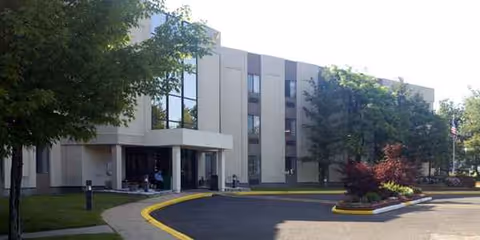 Exterior view of AristaCare at Cedar Oaks with entrance and curbside driveway.