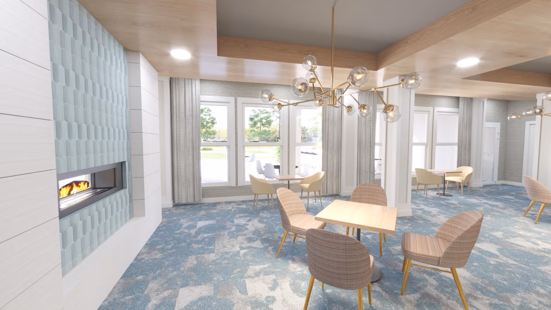 A modern, bright common area with light blue and gray patterned carpet, several small tables with chairs, large windows with curtains letting in natural light, and a contemporary fireplace with light blue tile surround. The ceiling has wooden beams and stylish light fixtures with multiple bulbs.