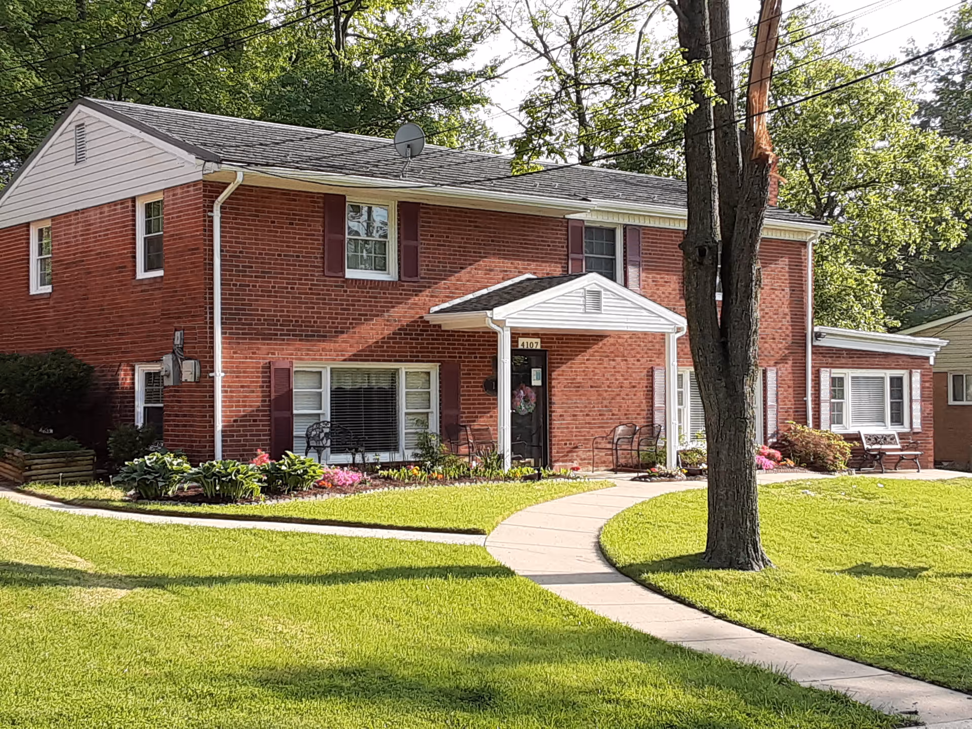 Brick senior living facility front exterior with curved walkway and landscaping.