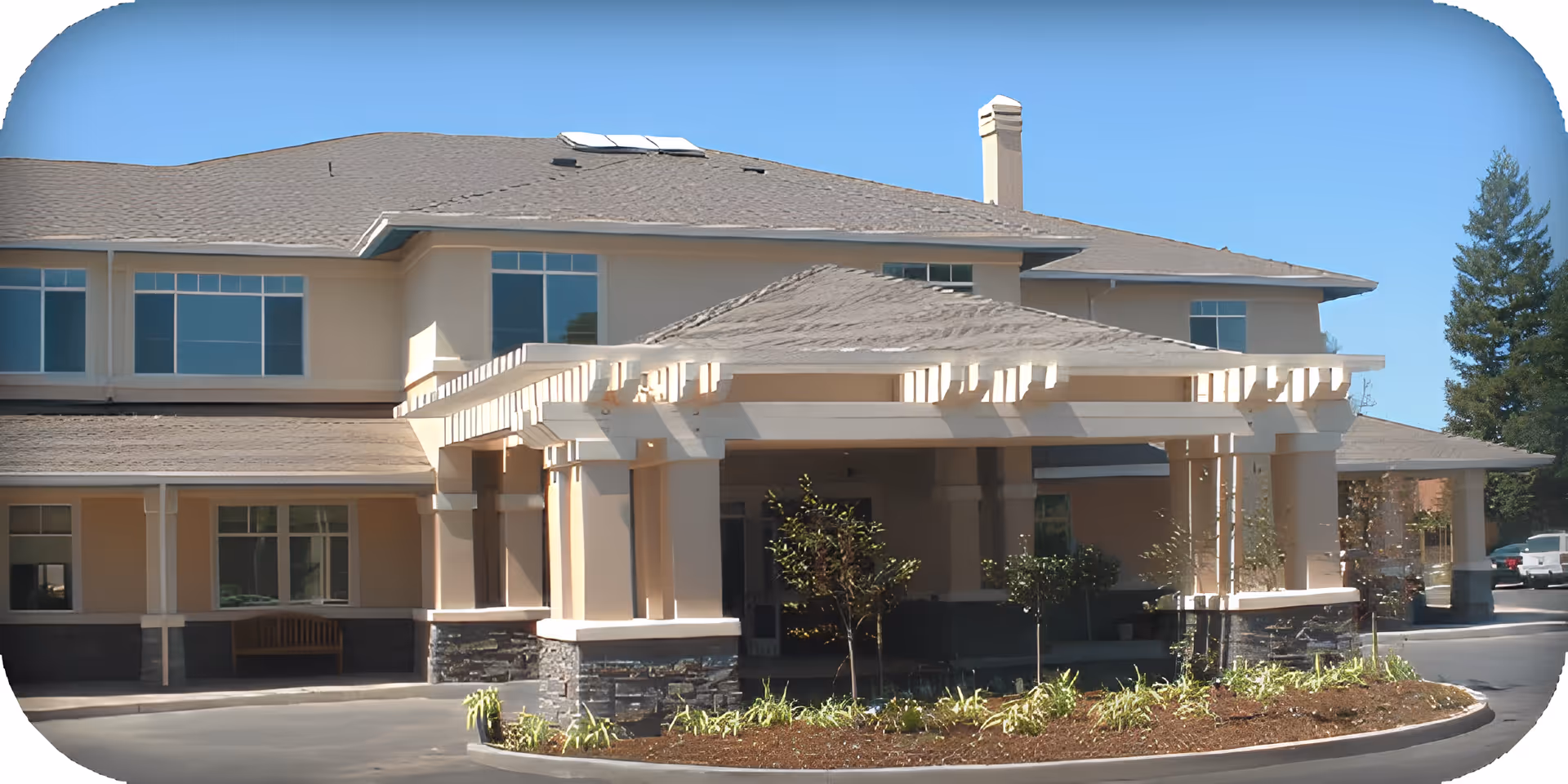 Covered main entrance and porte-cochere of the Stratford Beyer Park building with landscaping and a driveway.