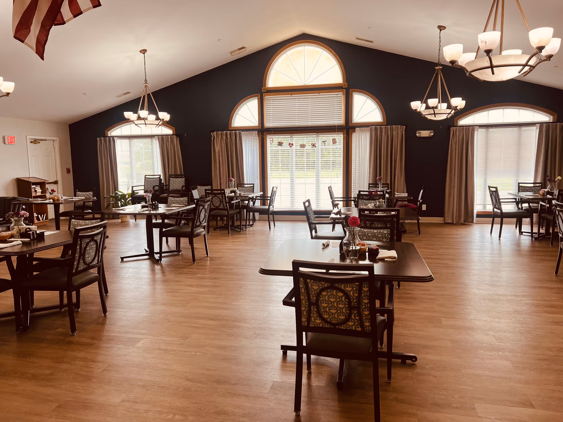 Spacious dining room with multiple tables, chairs, and large arched windows.