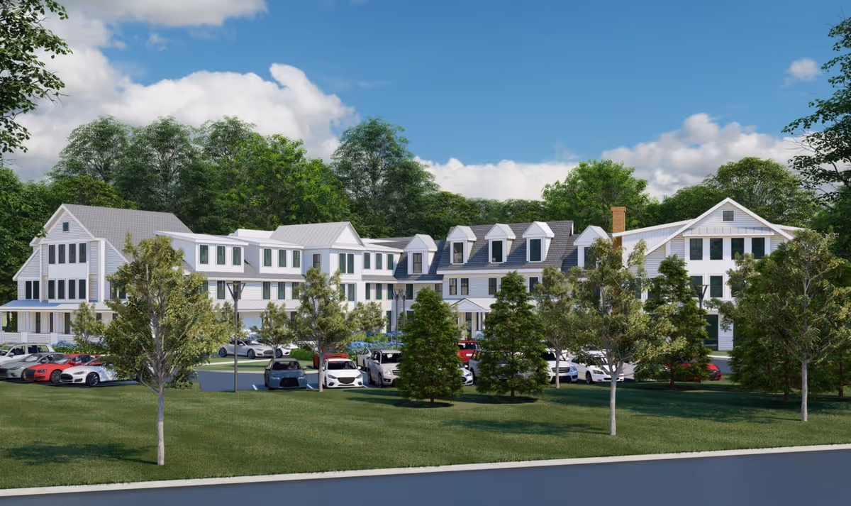 A multi-wing senior residence with front parking, manicured lawn, and white clapboard exterior.