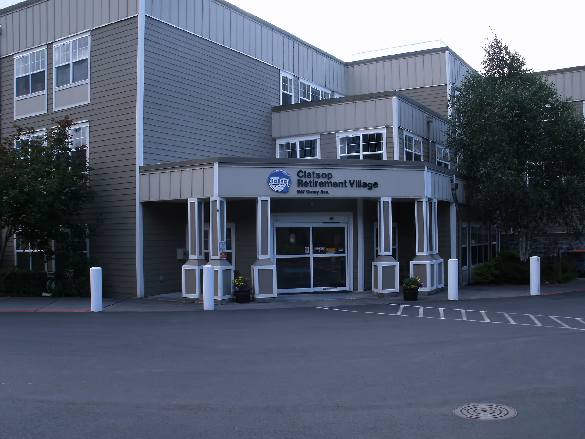 Front entrance of the Clatsop Retirement Village building with a covered drop-off and driveway.