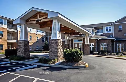 Exterior view of The Wellington at Dayton entrance featuring stone columns and a covered drive.