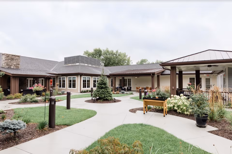 Landscaped courtyard with walkways, planters, seating, and a single-story memory care building surrounding it.