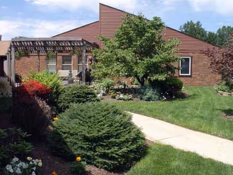 Meadow Wind Health Care Center brick building with a landscaped front garden and pergola.