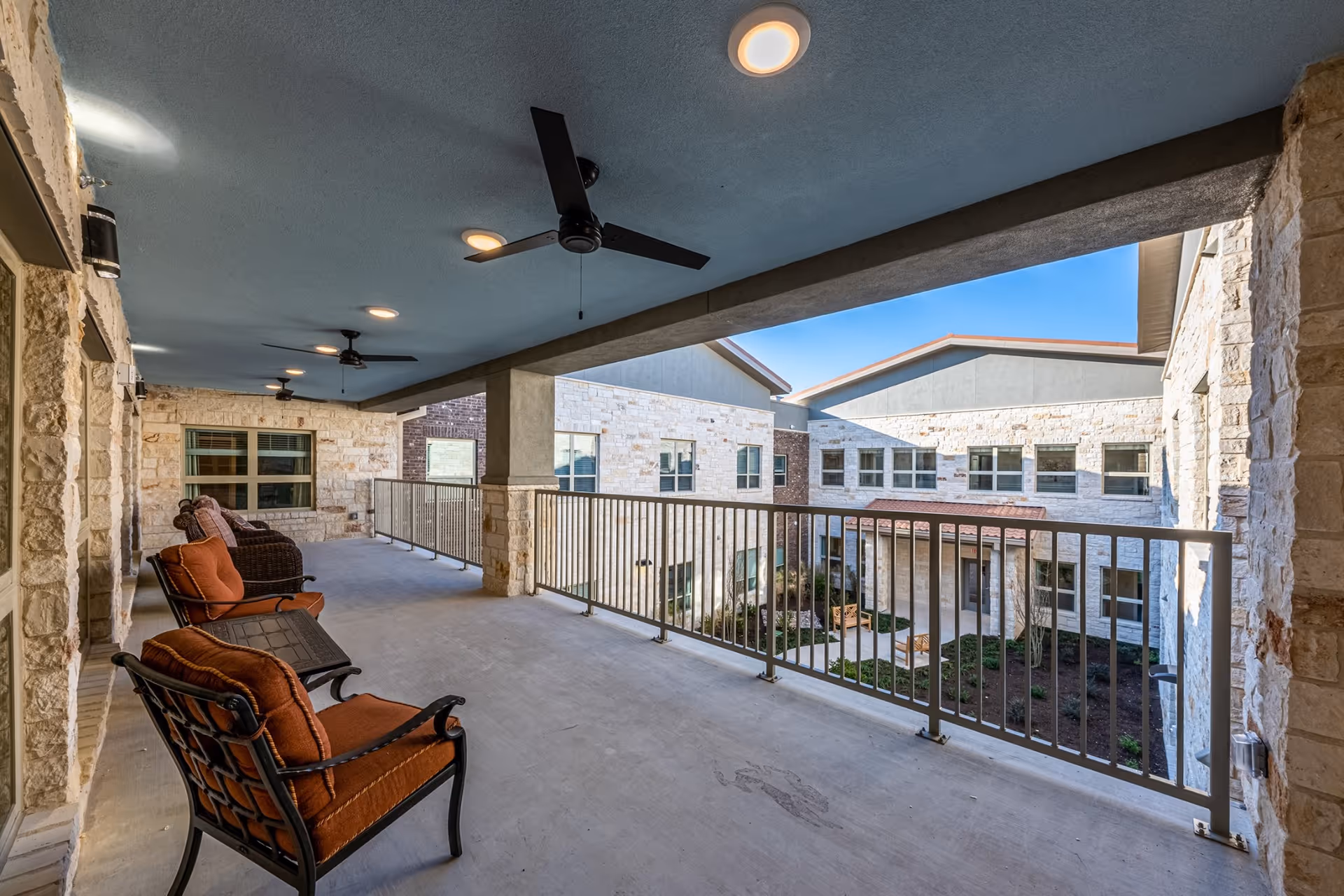 Covered outdoor patio at Buda Oaks with seating and ceiling fans overlooking the courtyard.
