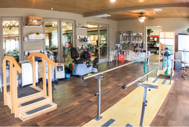 Interior therapy/rehab room with parallel bars, practice stairs, exercise equipment and walkers.