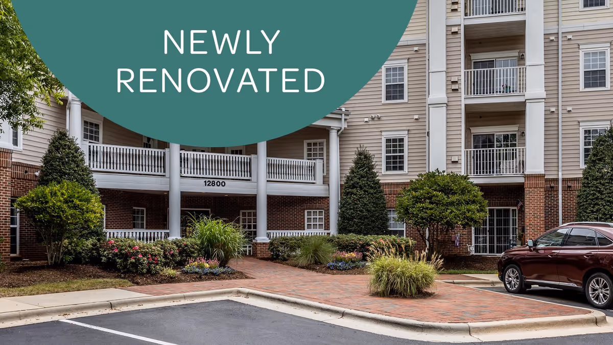 Front exterior of a multi-story senior living building with columns, balconies, landscaped entrance, a parked car, and a 'NEWLY RENOVATED' graphic overlay.