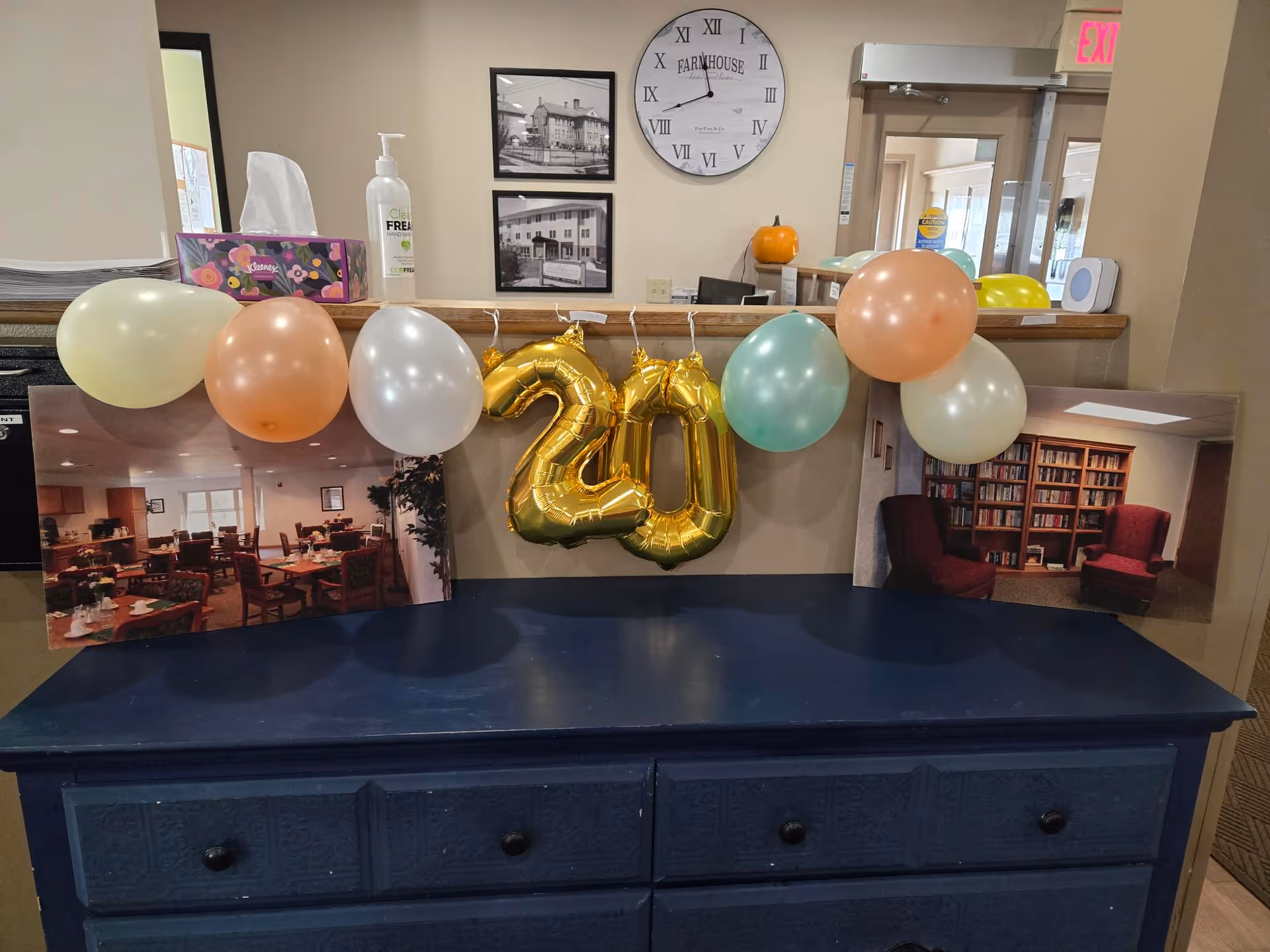 Reception counter inside a senior living community decorated with pastel balloons and a gold '20' balloon.
