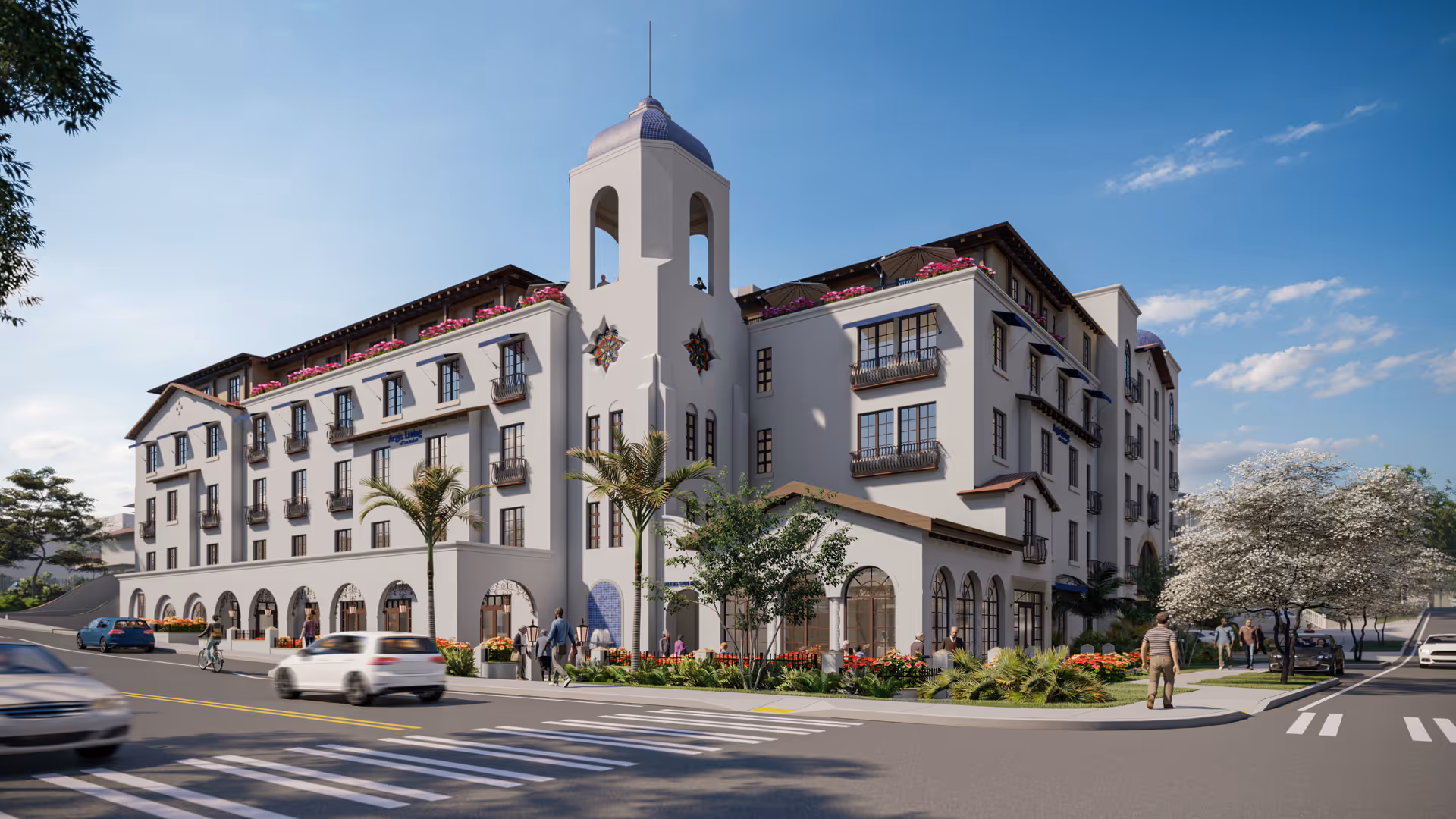 Exterior view of a multi-story senior living facility with Mediterranean architectural style, featuring arched windows, balconies with flower boxes, palm trees, and landscaped greenery along the sidewalk. People are walking on the sidewalks and cars are driving on the street in front of the building under a clear blue sky.