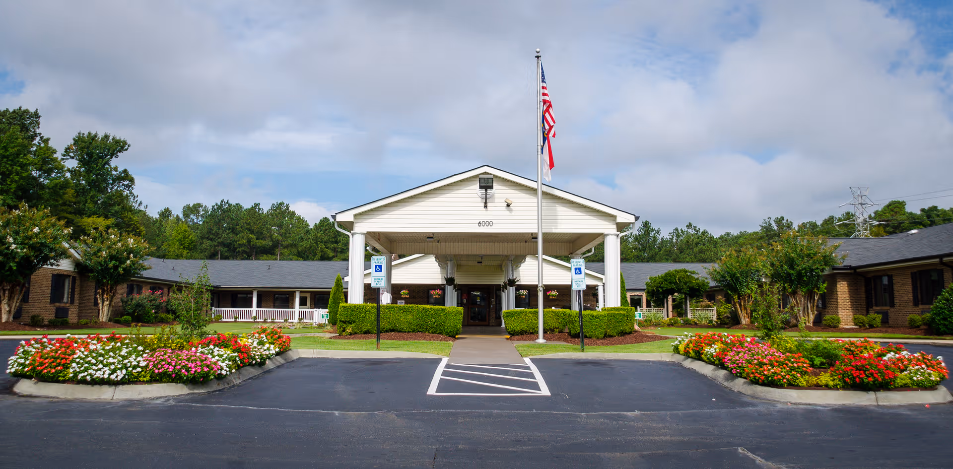 Front entrance of Southpoint Rehabilitation and Healthcare Center with flagpole, shrubs, and flowerbeds.