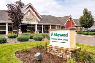 Front exterior of the Edgewood Senior Living building with a freestanding Edgewood sign, covered entrance, and landscaped grounds.