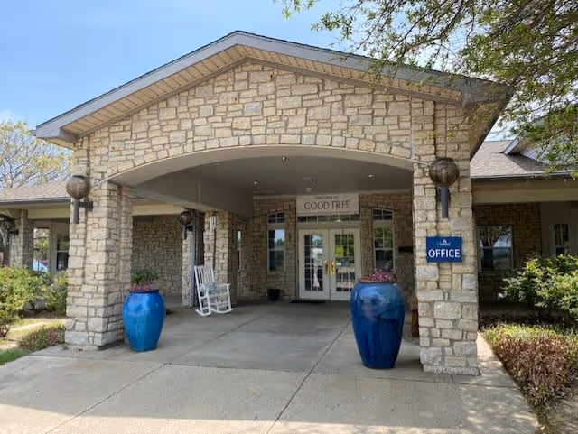 Entrance to the Good Tree facility with a stone façade, covered portico, two large blue planters and an 'Office' sign.