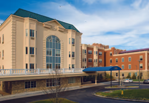 Exterior view of The Bristal Assisted Living at White Plains building with blue awning entrance.
