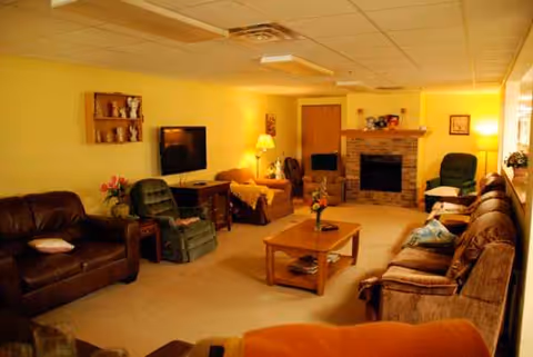 Cozy senior living lounge with sofas, chairs, a coffee table, and a fireplace.