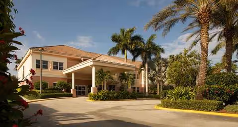 Front view of Chatsworth Assisted Living Community at PGA National with palm trees and entrance.