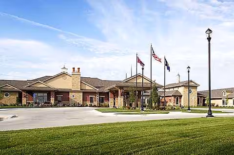 Exterior view of Brookestone Meadows senior living facility with flags and manicured lawn.