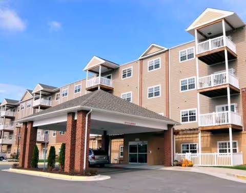 Exterior view of a multi-story senior living building with a covered entrance and balconies.