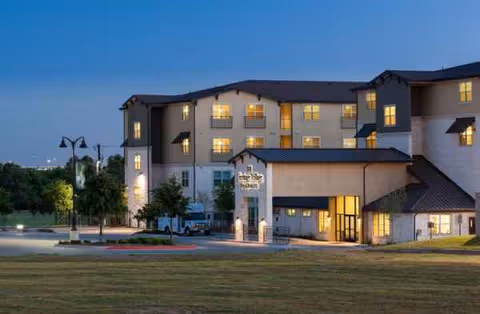 Exterior view of Heritage Village Residences building at dusk with illuminated entrance.