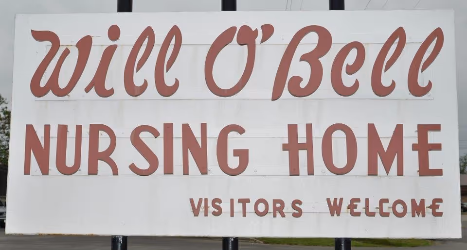 Large white outdoor sign reading 'Will O'Bell Nursing Home - Visitors Welcome.'