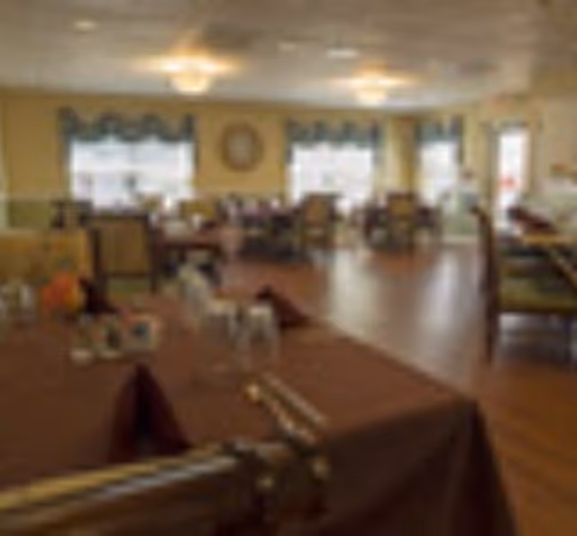 Spacious dining room with tables and chairs set for meals, windows, and ceiling lights.