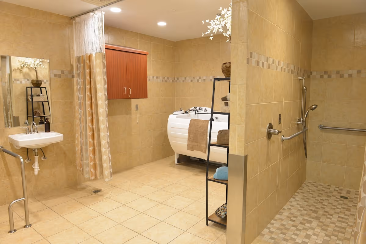 Spacious accessible tiled bathroom with a walk-in shower and grab bars, a wall-mounted sink, and a walk-in bathtub with shelving and towels.