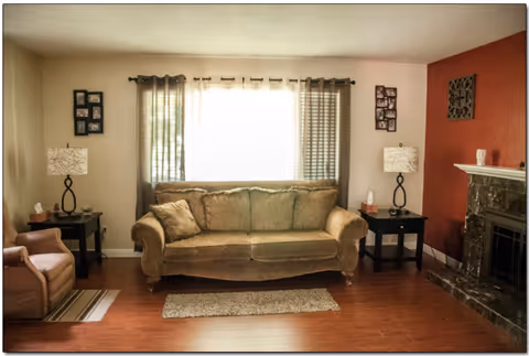 Cozy living room in a senior care home with sofa, lamps, and a fireplace.