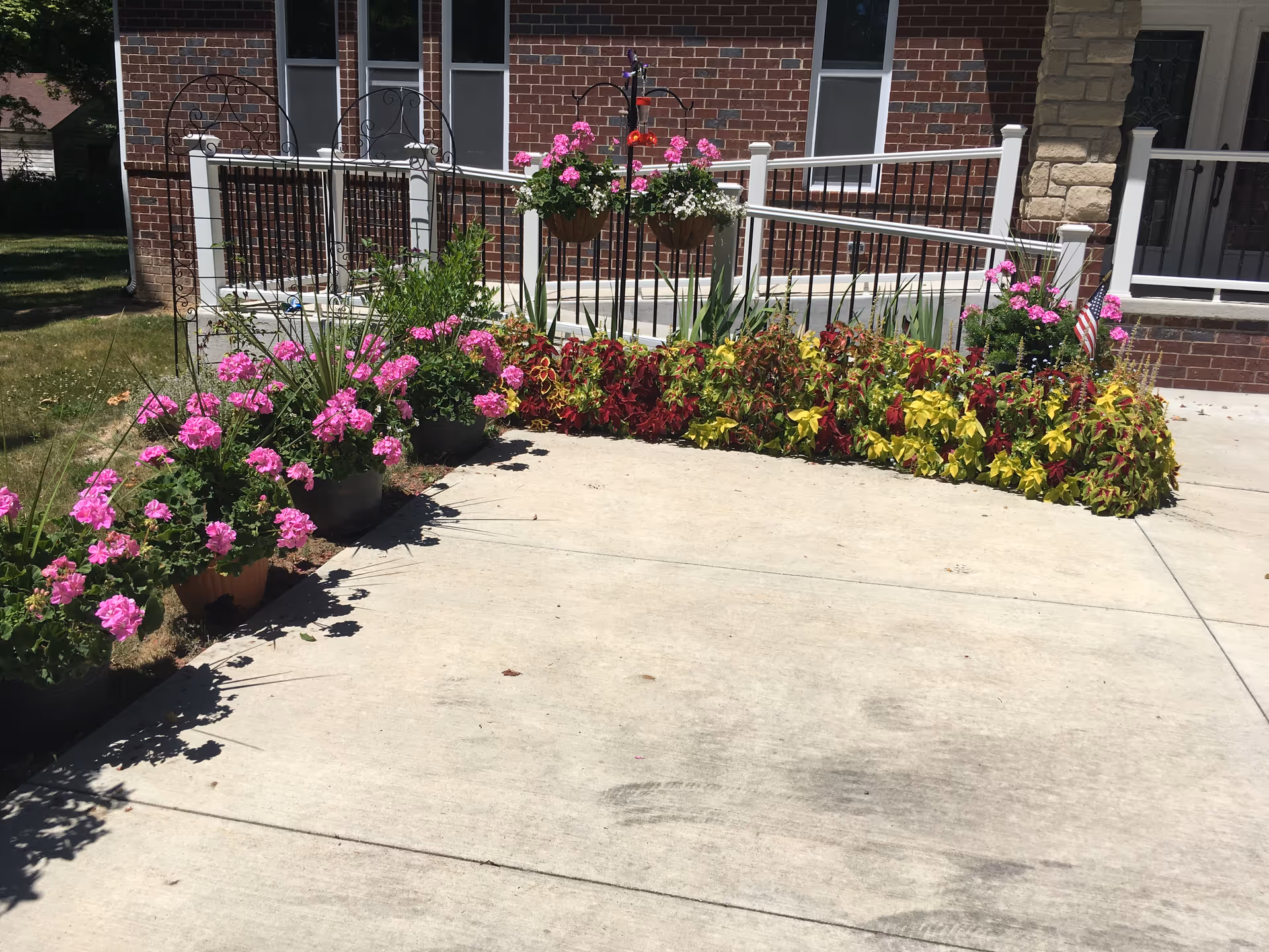 Front entrance with colorful flower planters along a brick building and railing.