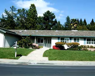 Single-story senior living facility exterior with a curved walkway and manicured lawn.