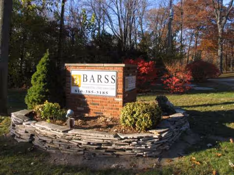 Lakeshore Woods entrance sign surrounded by stone landscaping and autumn trees.