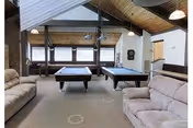 Community game room with two pool tables, sofas, and a vaulted wooden ceiling.