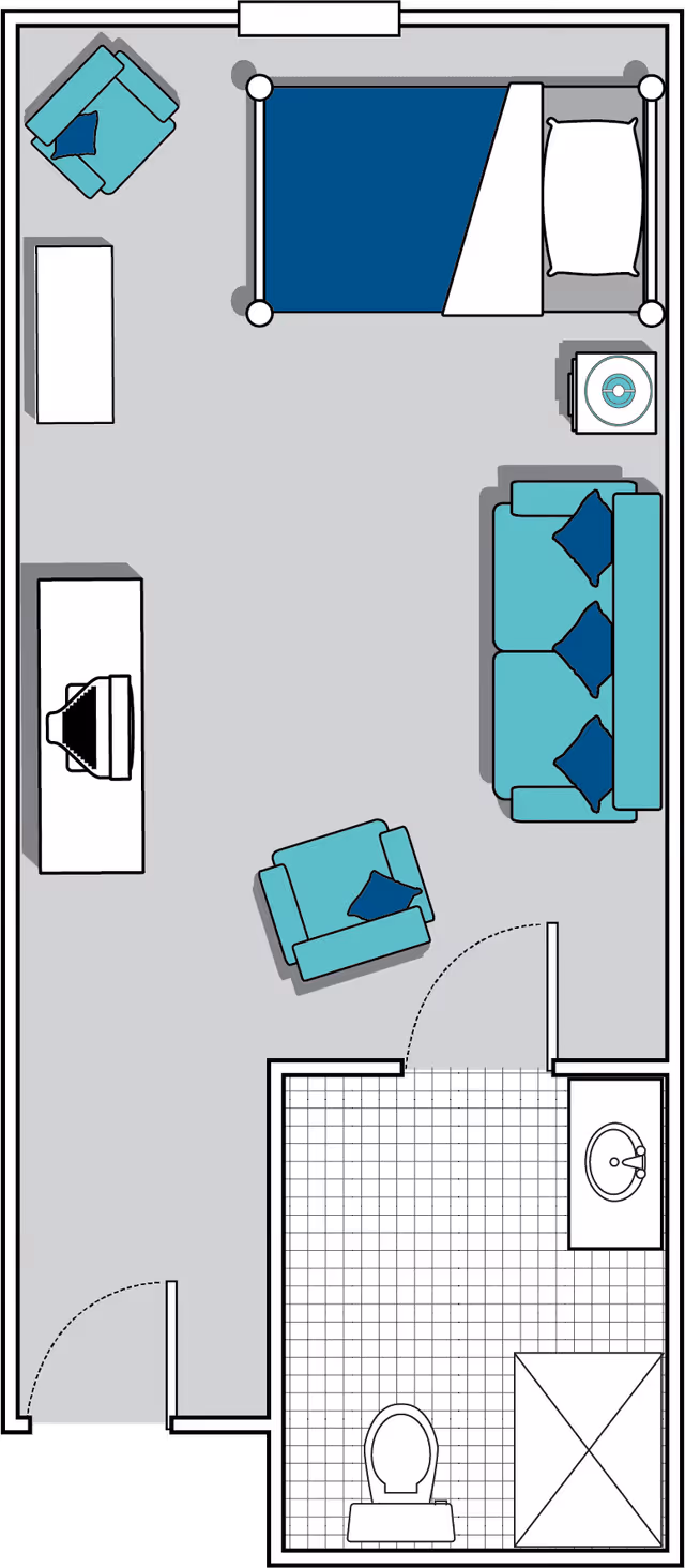 Floor plan of a studio apartment featuring a bed, sofa with three cushions, two armchairs with cushions, a TV on a stand, a small table with a lamp, and a bathroom with a toilet, sink, and shower.