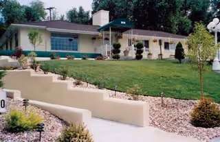 Single-story senior living facility building with a manicured front lawn, tiered landscaping, and an entry canopy.