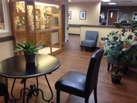 Lobby seating area with a round table, chairs, and potted plants.