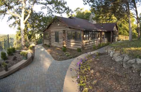 Log cabin-style senior living facility exterior with curved walkway and landscaped garden.