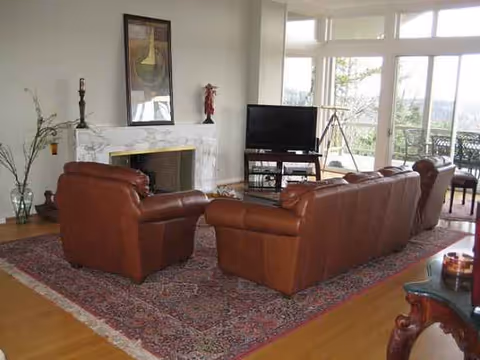 Brown leather sofas arranged around rug, fireplace, and TV in Riverview Adult Care Home living room