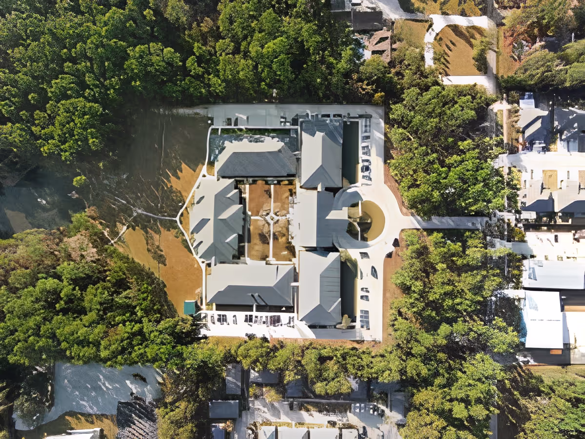 Aerial view of SummerHouse Park Provence facility surrounded by dense green trees, showing multiple buildings with gray roofs, pathways, and open areas within the property.