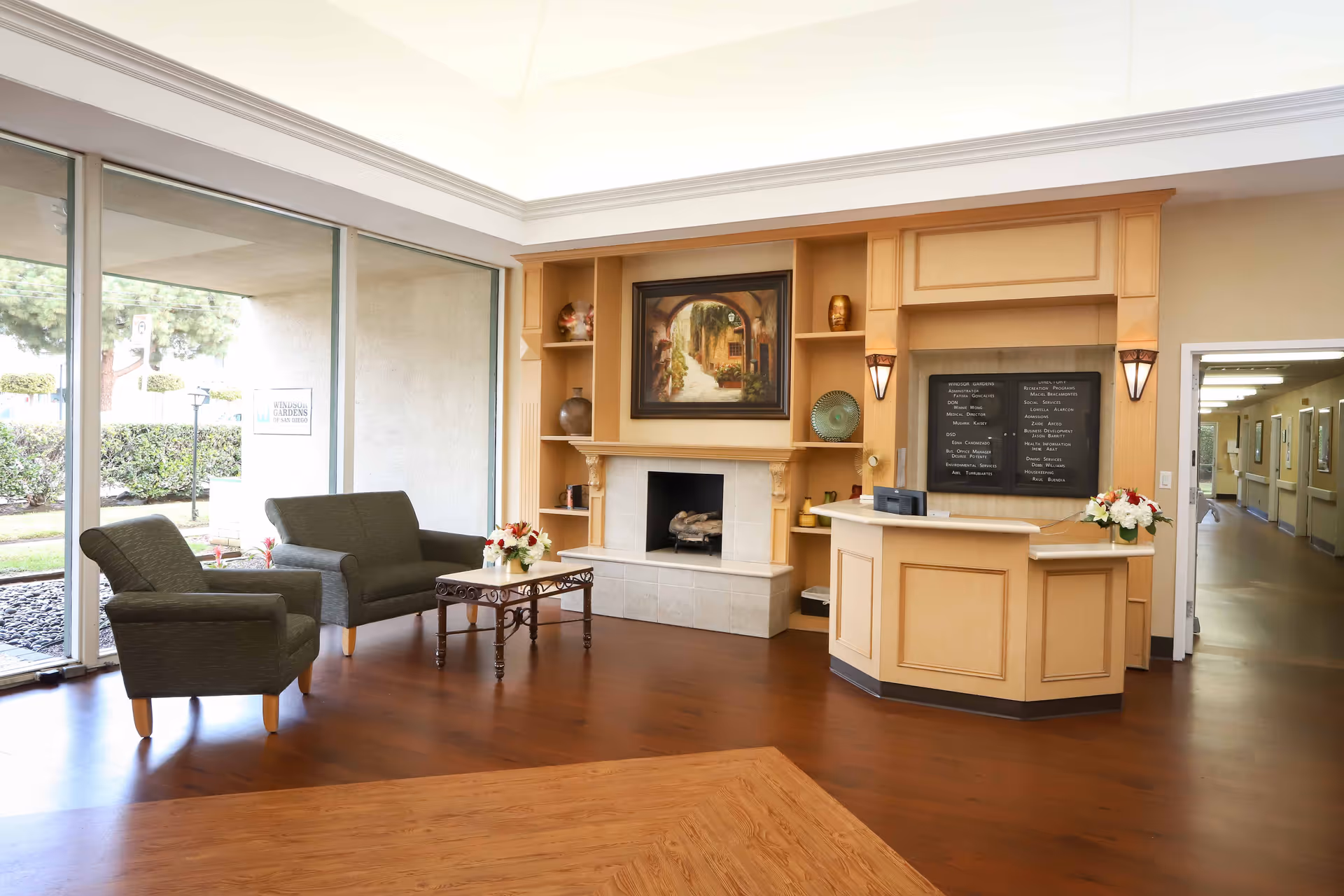 Bright reception lobby with seating, a fireplace, a front desk, and large windows looking outside.