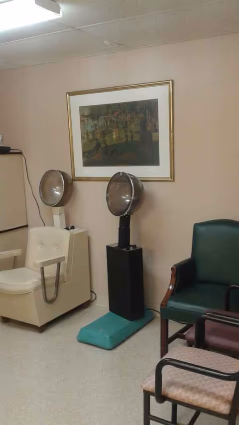 Interior of a senior living facility salon featuring two hooded hair dryers and seating.