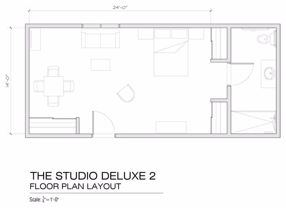 Architectural floor plan layout of The Studio Deluxe 2 showing a combined living and sleeping area with a bed, sofa, chair, dining table with four chairs, and a bathroom with a toilet, sink, and shower.