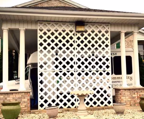 Front view of a senior living facility entrance with lattice screen and planters.
