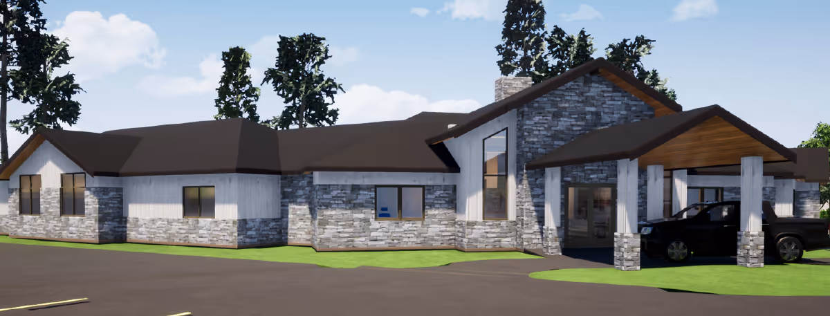 Front exterior of a single-story assisted living building with stone facade, a covered entrance/porte-cochere and a parked black pickup truck.