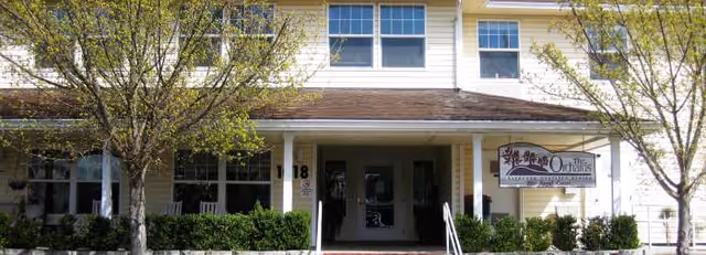 Exterior view of Orchards Assisted Living facility entrance with trees and shrubs.