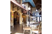 Indoor courtyard-style seating area with a round table, metal chairs, arches, and warm lighting.