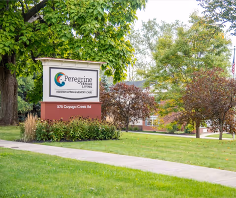 Freestanding sign for Peregrine Senior Living on a landscaped front lawn with the facility building and trees in the background.