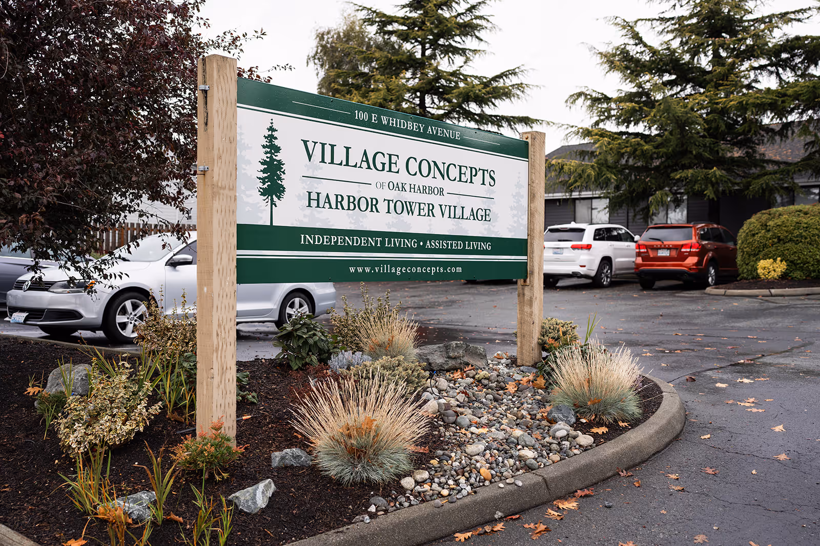 Entrance sign for Village Concepts of Oak Harbor - Harbor Tower Village in a landscaped parking lot.