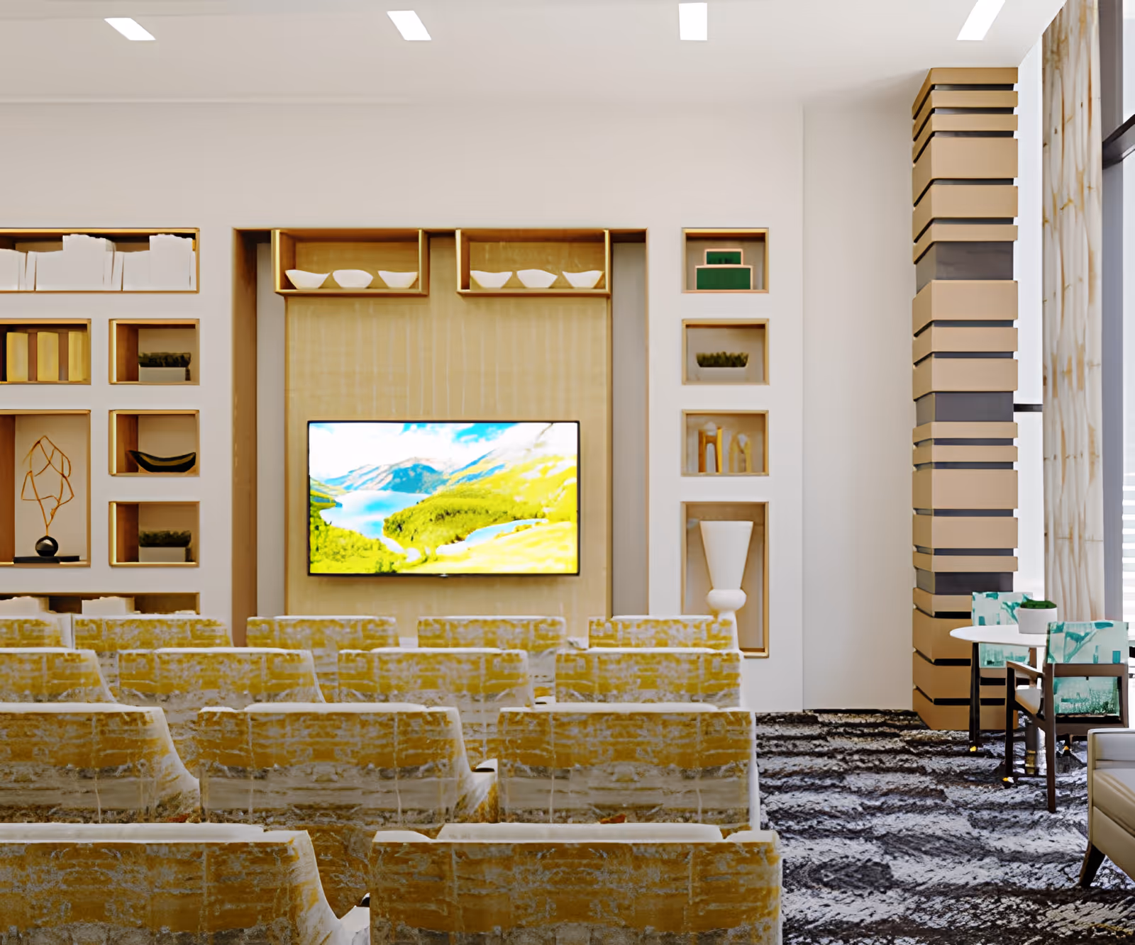 A bright communal seating area with rows of yellow patterned chairs facing a wall-mounted TV and built-in shelving.